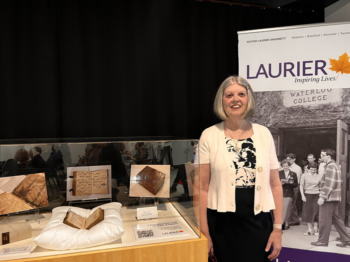 Alma Santosuosso smiling beside the noted hymnal in a display case.