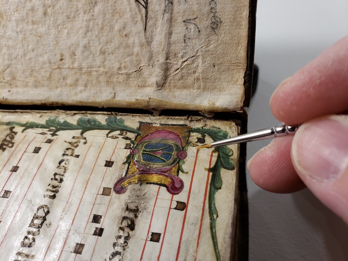 A small paintbrush is being used to apply an adhesive solution to the pigment.