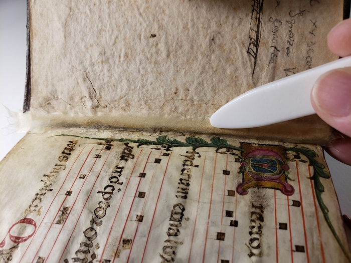 Jennifer Robertson adhering Japanese paper to the joint between the pages and cover of the Hymnal to strengthen the binding.